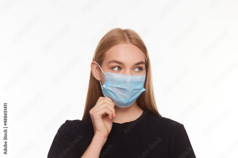 blond young woman wearing medical mask adjusting it with her hands close up blond young woman wearing medical mask adjusting it with her hands close up