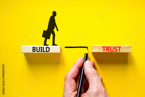 Build trust symbol. Concept words Build trust on wooden blocks on a beautiful yellow table yellow background. Businessman hand. Business and build trust concept, copy space. photo