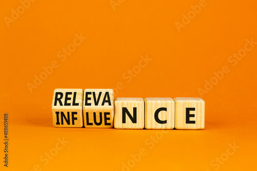 Influence or relevance symbol. Turned wooden cubes and changed the word Influence to Relevance. Beautiful orange table orange background. Business influence or relevance concept. Copy space. photo