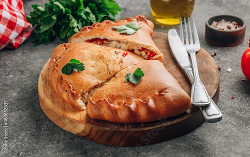Bild auf Leinwand Italian food, closed pizza calzone with cheese, gray stone background