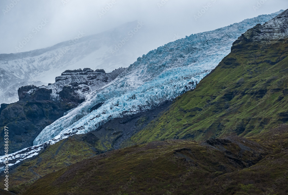 View from highway road during auto trip in Iceland. Spectacular Icelandic landscape with  scenic nature: hamlets, mountains, ocean coast, fjords, fields, clouds, glaciers, waterfalls.