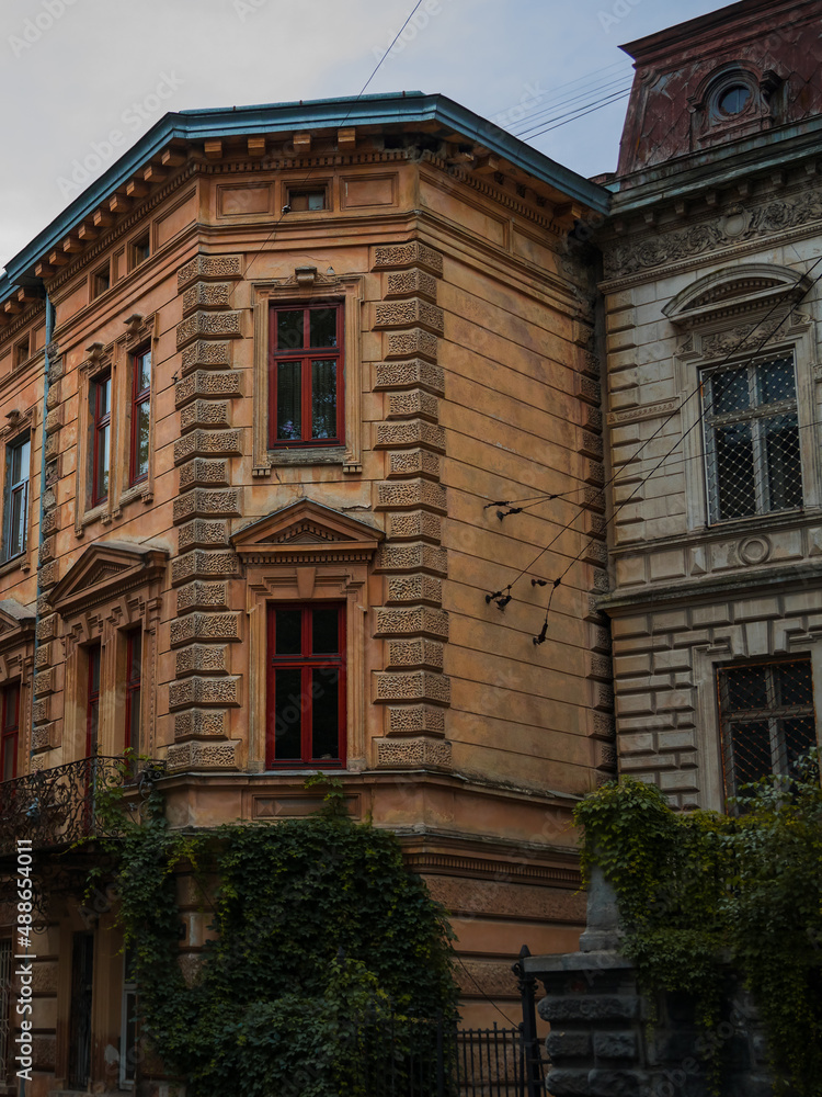 Naklejka premium autumn old Europe city living district apartment building rustic stone exterior facade of front side vertical photography on fall season rainy gray day time