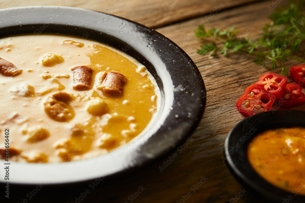Mote pata is a traditional ecuadorian soup made from mote, pork, sausage and sambo seeds. It’s served on a white plate with a rustic, wooden and homey background. Mote pata is a traditional ecuadorian soup made from mote, pork, sausage and sambo seeds. It’s served on a white plate with a rustic, wooden and homey background.