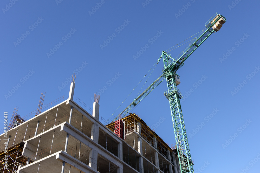 A working crane against a blue sky. Crane above the construction site. Industrial background. A working crane against a blue sky. Crane above the construction site. Industrial background.