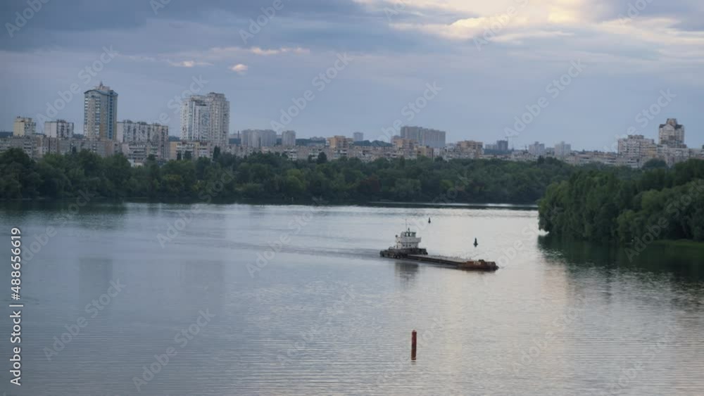 Drone shot cityscape at flowing river evening. Tow boat pushing old empty barge Drone shot cityscape at flowing river evening. Tow boat pushing old empty barge