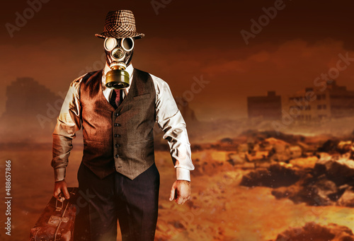 Photo of post apocalyptic male citizen in formal outfit, hat, gas mask and suitcase walking on destroyed city nuclear war wasteland. photo