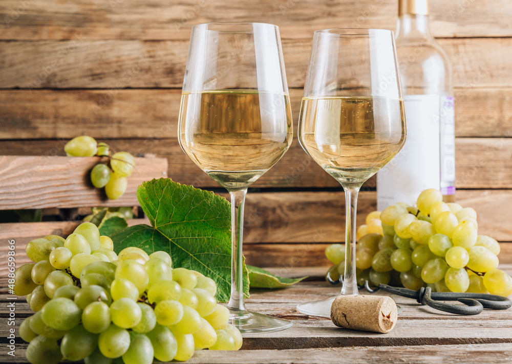 Two glasses of white wine and grape on vintage wooden table