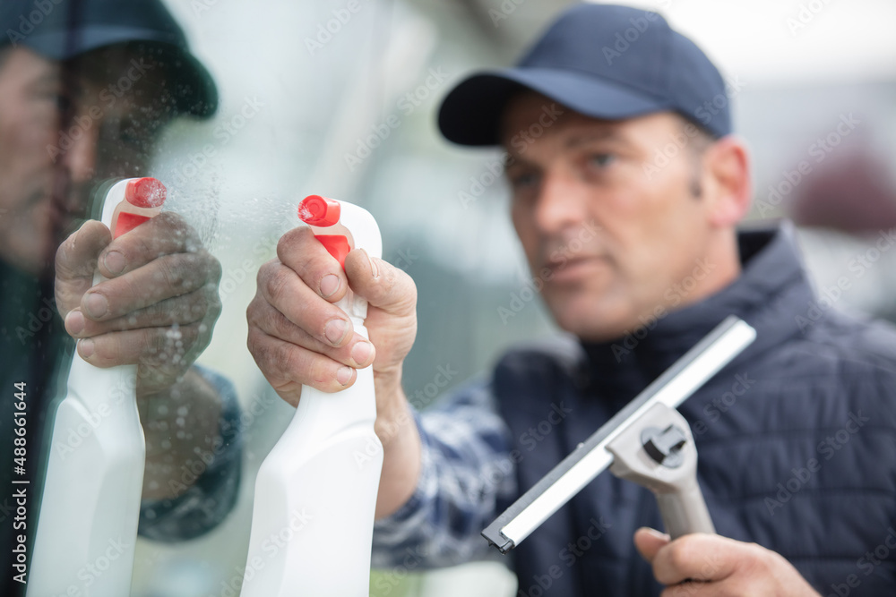 adult worker cleaning glass window with squeegee adult worker cleaning glass window with squeegee