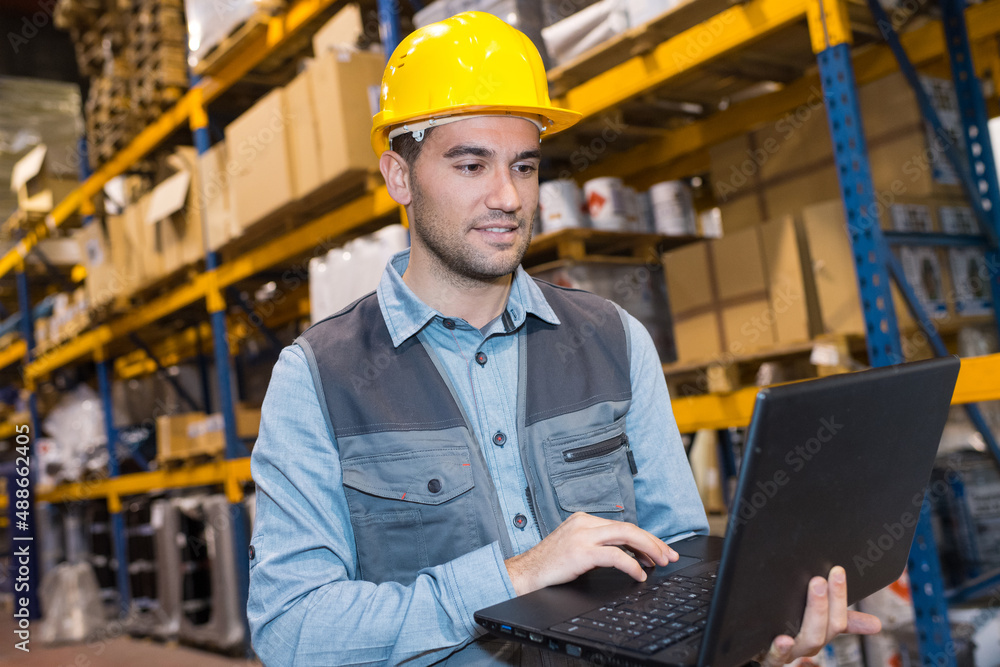 portrait of worker in warehouse with laptop computer portrait of worker in warehouse with laptop computer