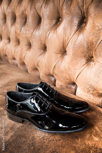 Luxurious black shiny patent leather shoes on a brown cabinet.
