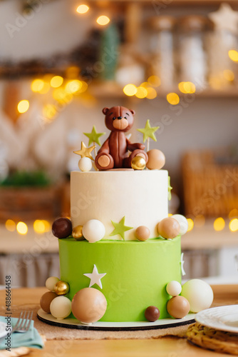 two-tiered white-green cake with balls, stars and teddy bear for birthday.