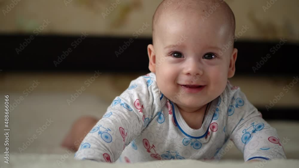 Newborn Active Baby Cute Smiling Teethless Face Portrait Early Days On Stomach Developing Neck Control. 5 Months Child On White Bed Looking on Camera. Infant, Childbirth, Parenthood, Beginning Concept Newborn Active Baby Cute Smiling Teethless Face Portrait Early Days On Stomach Developing Neck Control. 5 Months Child On White Bed Looking on Camera. Infant, Childbirth, Parenthood, Beginning Concept