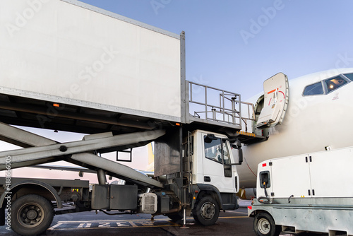 Close-up detail view of highloader cargo catering service truck loading commercial passenger aicraft with food sets and parcel shipping. Airport plane maintenance handling. GPU connect and cleaning
