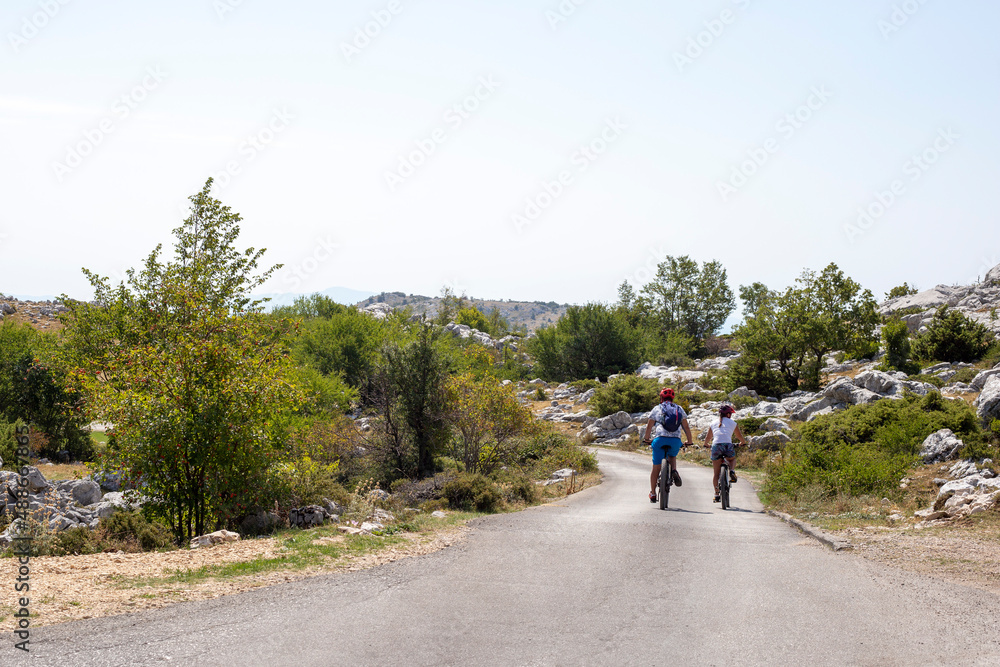 Man and woman ride bicycles on mountain road in summer Man and woman ride bicycles on mountain road in summer