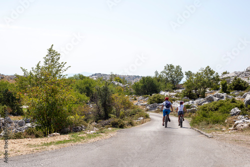 Man and woman ride bicycles on mountain road in summer