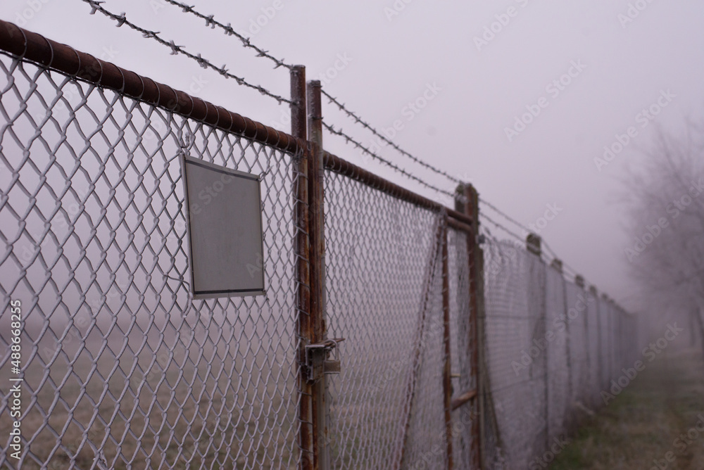 Barbed wire fence and locked gate on a misty winter day. Barbed wire fence and locked gate on a misty winter day.