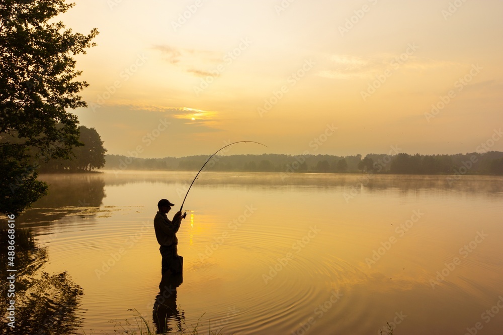 angler catching the fish during sunrise