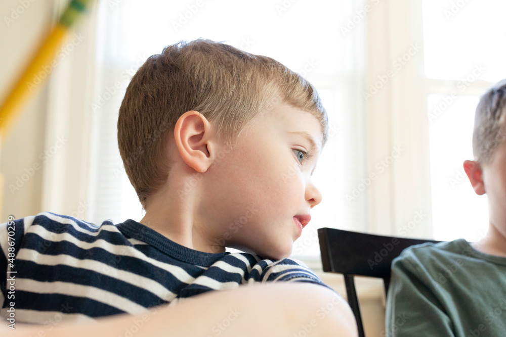 Mid Shot of Young Boy Looking Over Shoulder While Holding Pencil