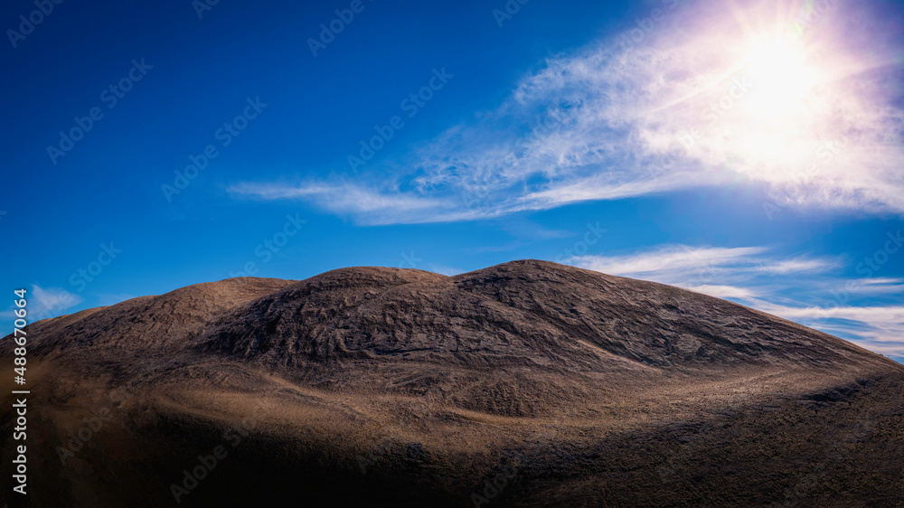 Panoramic majestic hilltop landscape of wilderness sand dunes illuminated by the glowing sun in the blue sky with white clouds