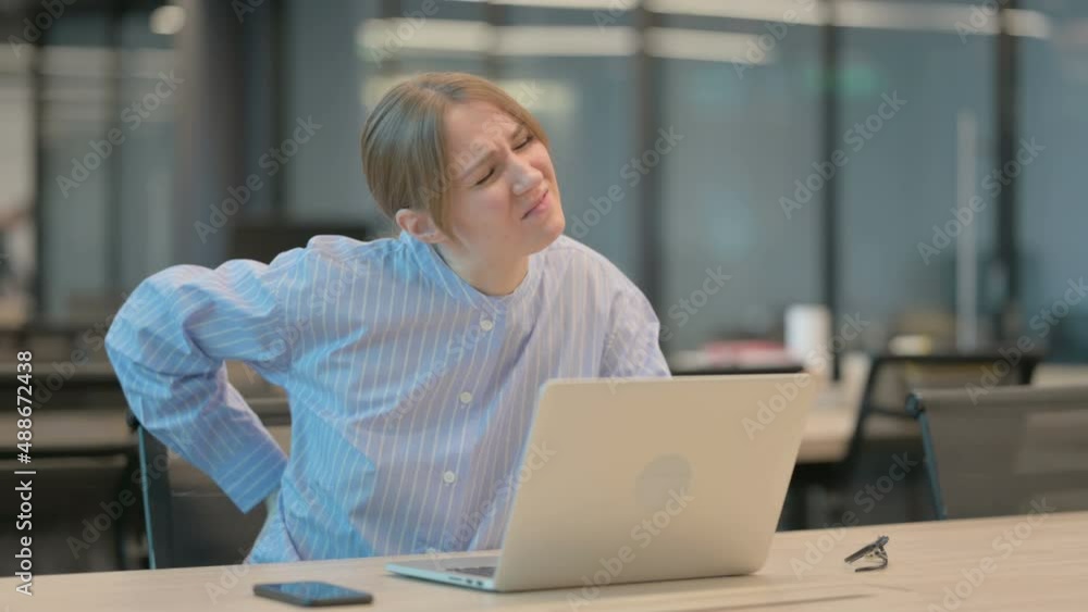 Young Woman having Back Pain while using Laptop in Office Young Woman having Back Pain while using Laptop in Office