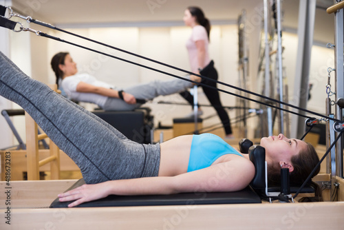 Woman exercising torson rotation at gym using pilates reformer beds