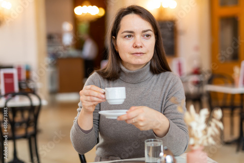 Portrait of female tourist enjoying cup of tasty fragrant espresso in cozy Viennese coffee house.. photo