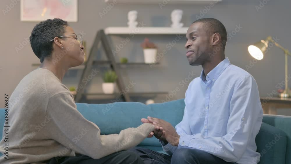 Loving African Man Talking to African Woman while Sitting on Sofa Loving African Man Talking to African Woman while Sitting on Sofa