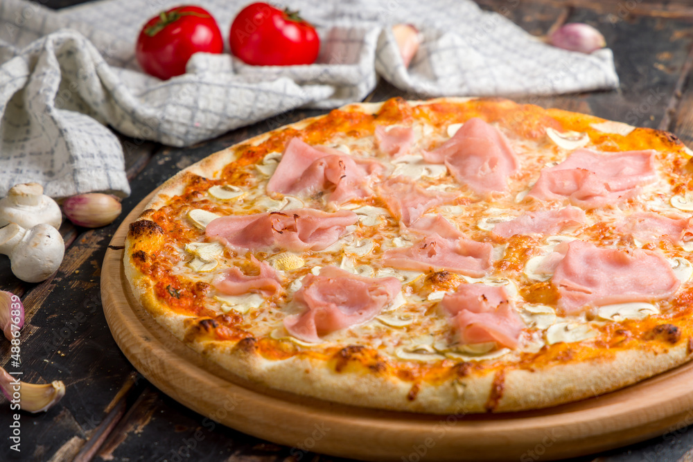 Pizza with ham and mushrooms with steam on old wooden table macro close up