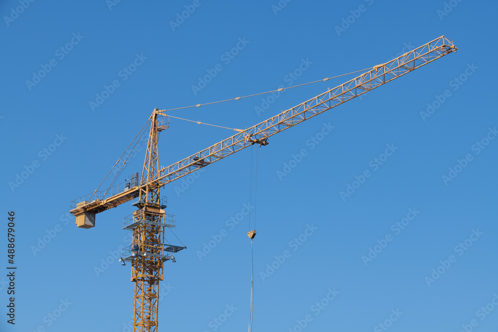 View of a tower crane installed at a construction site on a clear sky background