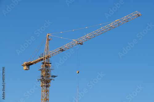 View of a tower crane installed at a construction site on a clear sky background