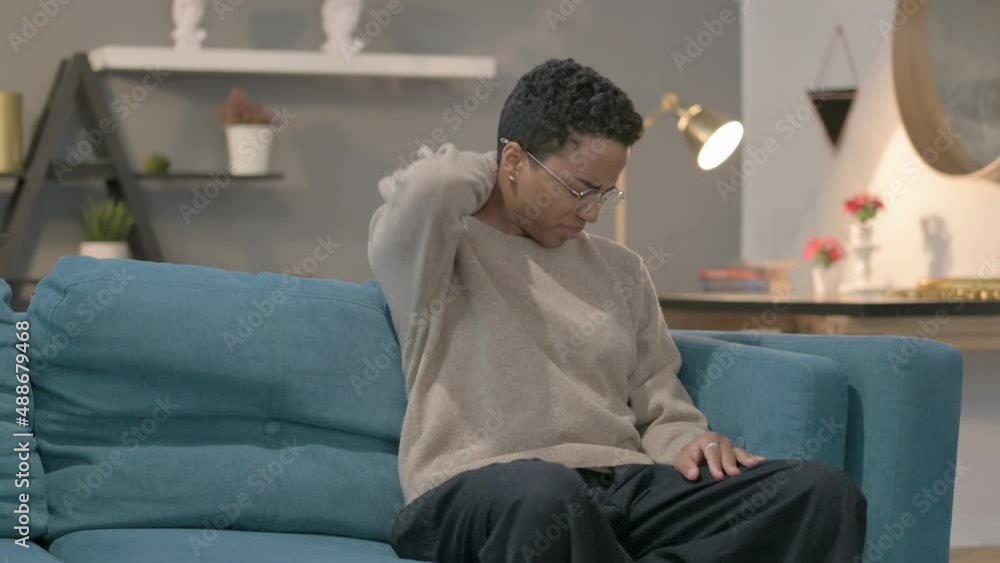African Woman having Neck Pain while Sitting on Sofa African Woman having Neck Pain while Sitting on Sofa