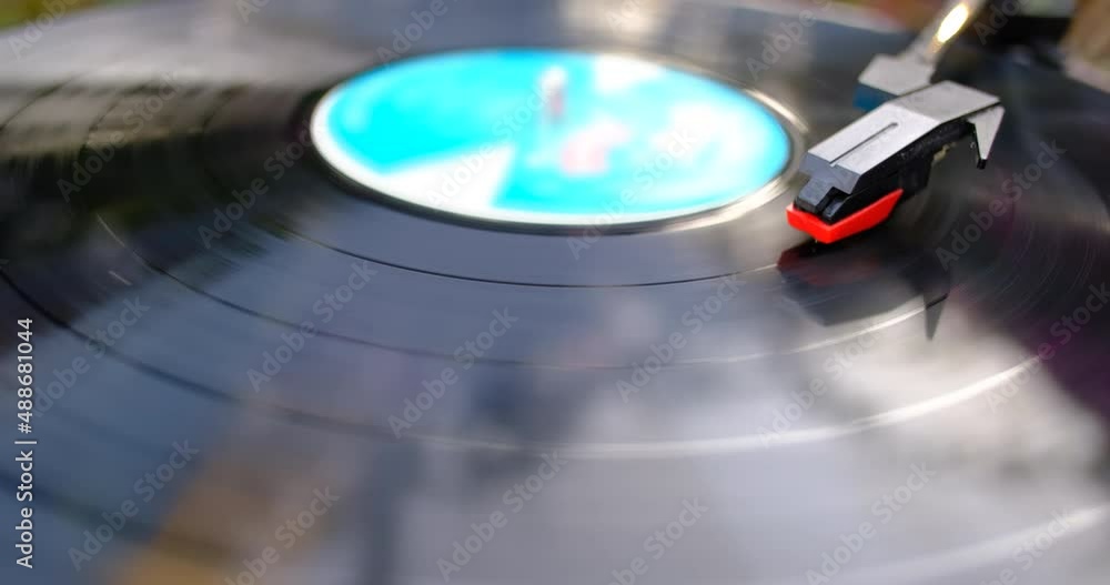 Turntable is spinning with a phono cartridge on the Vinyl. Vintage music player in the garden. Turntable is spinning with a phono cartridge on the Vinyl. Vintage music player in the garden.