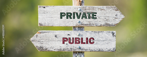 opposite signs on wooden signpost with the text quote private public engraved. Web banner format. photo