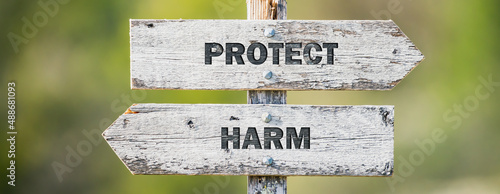 opposite signs on wooden signpost with the text quote protect harm engraved. Web banner format.