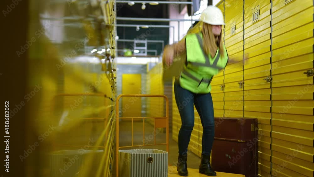 Wide shot excited cheerful woman dancing on industrial trolley in yellow warehouse indoors. Joyful female Caucasian employee having fun rejoicing indoors in storage. Happiness and lifestyle concept Wide shot excited cheerful woman dancing on industrial trolley in yellow warehouse indoors. Joyful female Caucasian employee having fun rejoicing indoors in storage. Happiness and lifestyle concept