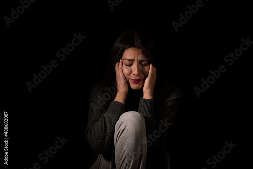 Latin young woman suffering depression on isolated black background
