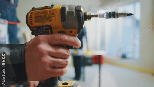 Hands man holding electric screwdriver with light in the building. Pulls out of the case and turns on. Then turns off and puts in place. Professional tools for construction. Slow motion photo