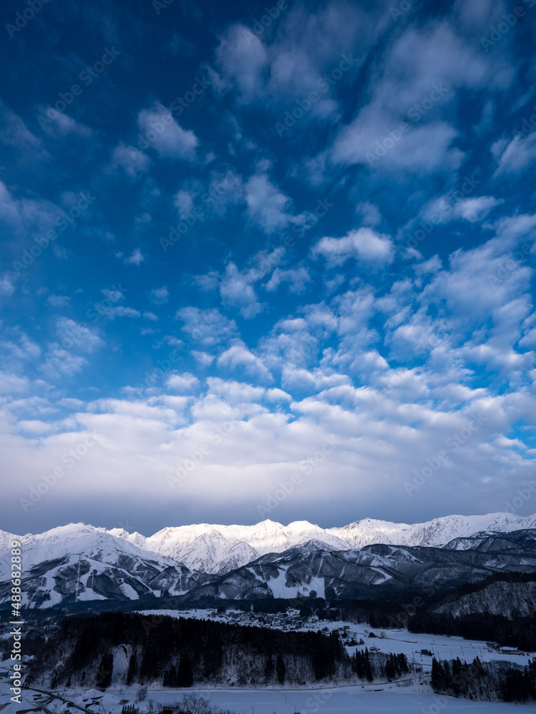 高台からの朝方の冬景色、白銀の街並みと白馬連峰を見渡す、青空には一面のウロコ雲が広がっている。