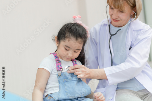 Female doctor examining a little cute girl by stethoscope, Kid on consultation at the pediatrician. Healthcare and medicine concepts