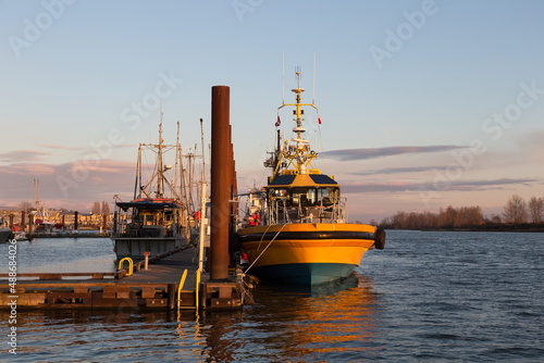 Boats docked in the Steveston heritage fishing village marina at the mouth of the Fraser River during a golden hour winter sunset, Richmond, British Columbia, Canada