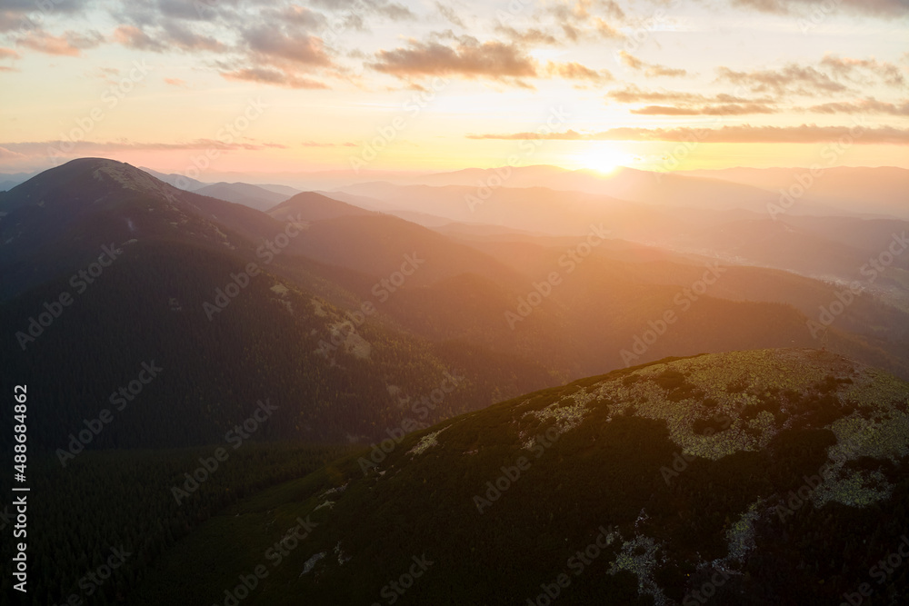 Aerial view of bright foggy morning over dark peak with mountain forest trees at autumn sunrise. Beautiful scenery of wild woodland at dawn Aerial view of bright foggy morning over dark peak with mountain forest trees at autumn sunrise. Beautiful scenery of wild woodland at dawn