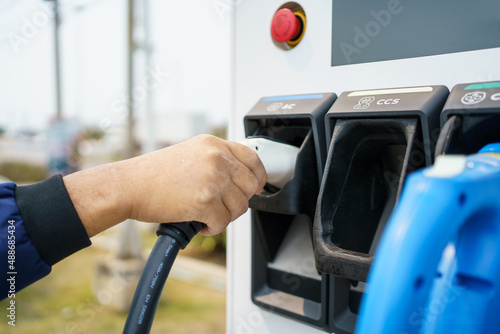 Asian man preparing to charge his electric car or EV at charging station.