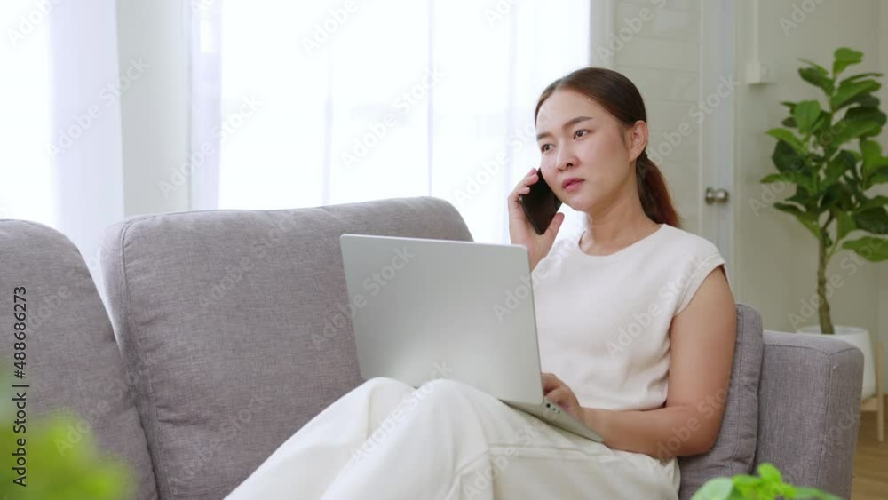 Asian woman talking on the phone working at home Asian woman talking on the phone working at home