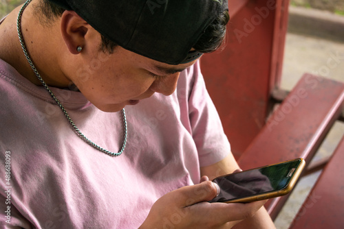 Close up of a young man using his cellphone. Urban style, youth and social media.
