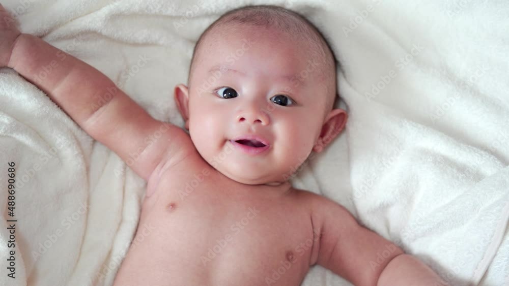 Adorable, Asian newborn laying with white blanket on bed in bedroom. Baby boy looking camera and laughing smile happy face. Little innocent new infant child in first day of life. Mother day concept. Adorable, Asian newborn laying with white blanket on bed in bedroom. Baby boy looking camera and laughing smile happy face. Little innocent new infant child in first day of life. Mother day concept.