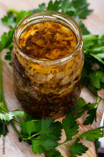 Jar of homemade marinated herring with onion, assorted peppers, vinegar, olive oil, sea salt