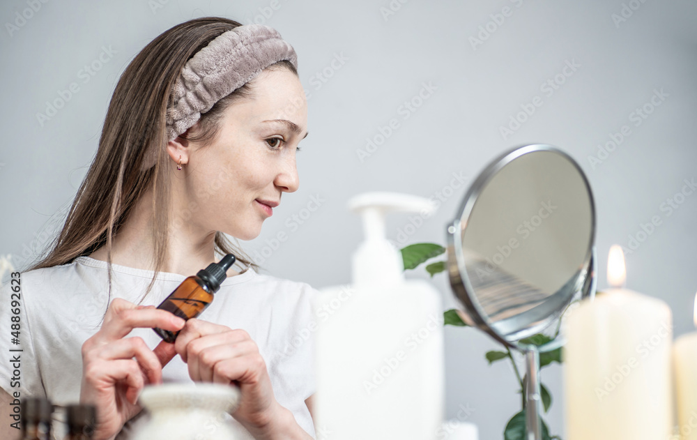 Woman with a bottle of cosmetic natural organic oil for skin care. Concept of natural organic cosmetics, morning and evening rituals Woman with a bottle of cosmetic natural organic oil for skin care. Concept of natural organic cosmetics, morning and evening rituals