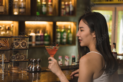 Asian women drinking cocktails and having fun at the bar at night.