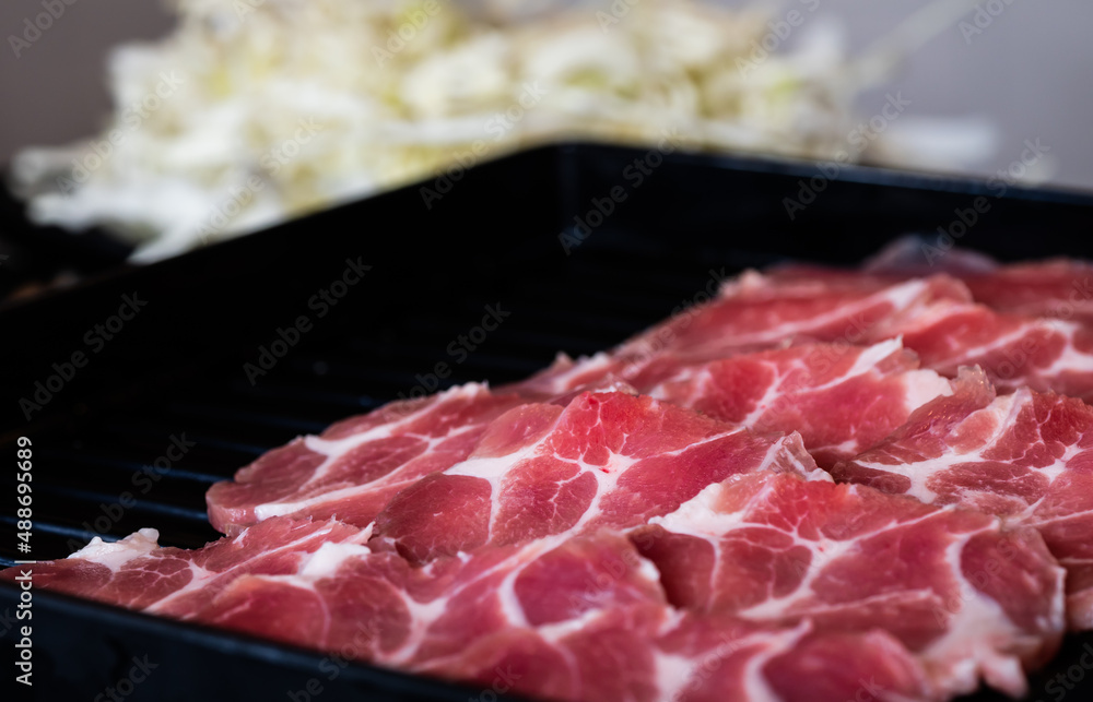 To serve for barbecue, pork is cut into thin, circular plates and set in a black tray. To serve for barbecue, pork is cut into thin, circular plates and set in a black tray.
