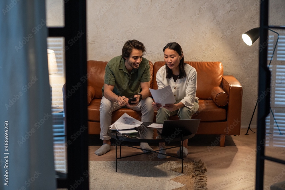 Young Asian female auditor with financial documents making report or presentation of new project to businessman with smartphone Young Asian female auditor with financial documents making report or presentation of new project to businessman with smartphone